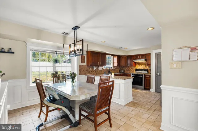 a kitchen with a dining table chairs and refrigerator