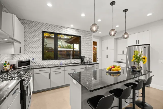 a kitchen with stainless steel appliances granite countertop a sink a stove a dining table and chairs
