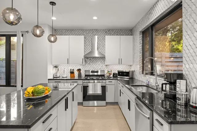 a kitchen with stainless steel appliances granite countertop a sink a stove and a wooden cabinets