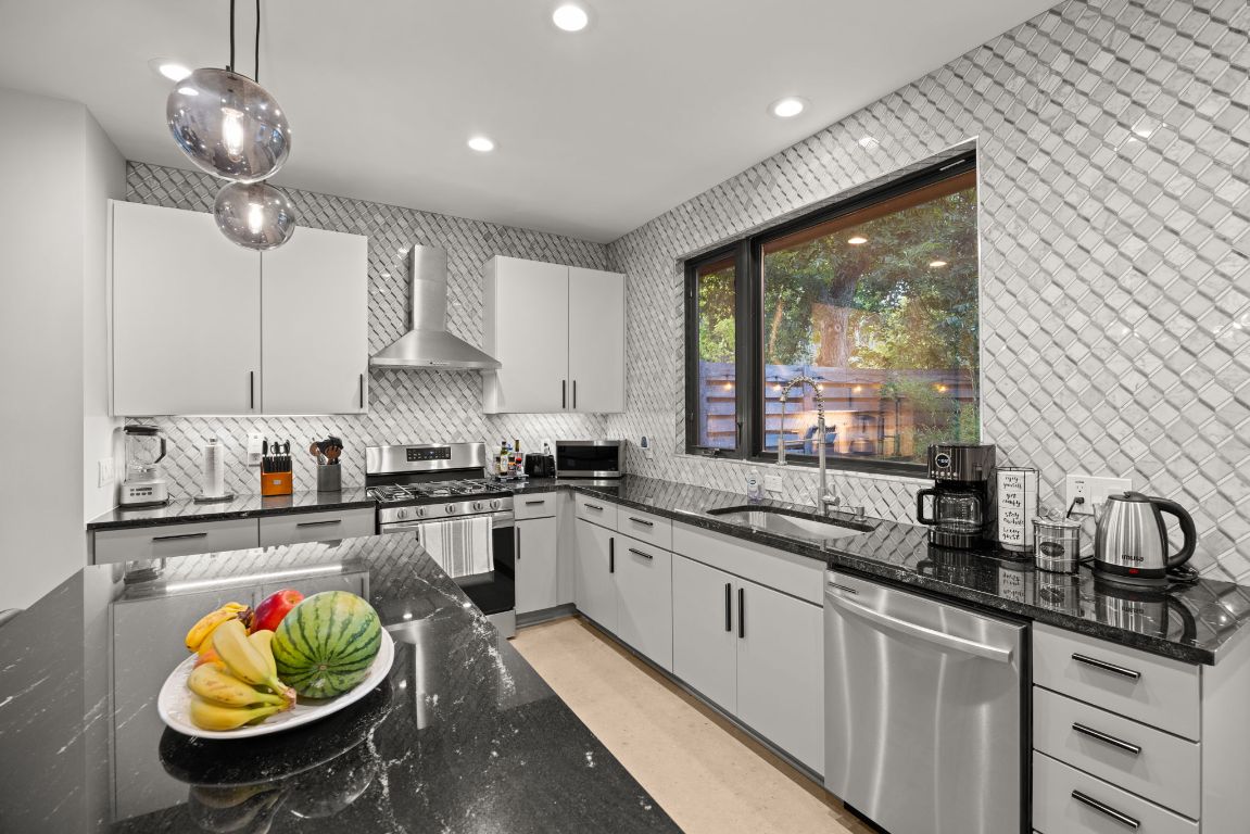 3610 Thompson Street, Unit 1 Austin, TX 78702 - Photo 19 of 39 a kitchen with stainless steel appliances granite countertop a sink a stove and a wooden floors