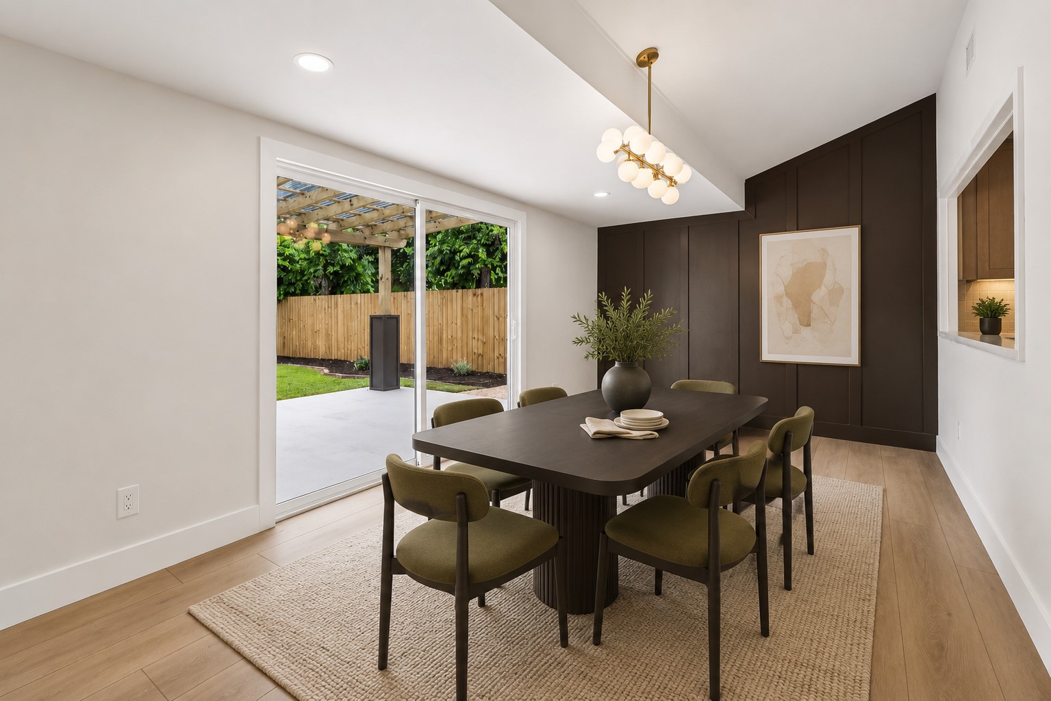 11809 Charing Cross Road Austin, TX 78759 - Photo 10 of 34 Elegant dining space, showcasing rich wall paneling and a modern chandelier, connects seamlessly to an outdoor patio with a pergola.