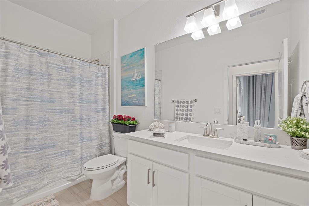 5513 Little Path Drive Wimauma, FL 33598 - Photo 24 of 40 a bathroom with a toilet a sink a mirror a window and vanity