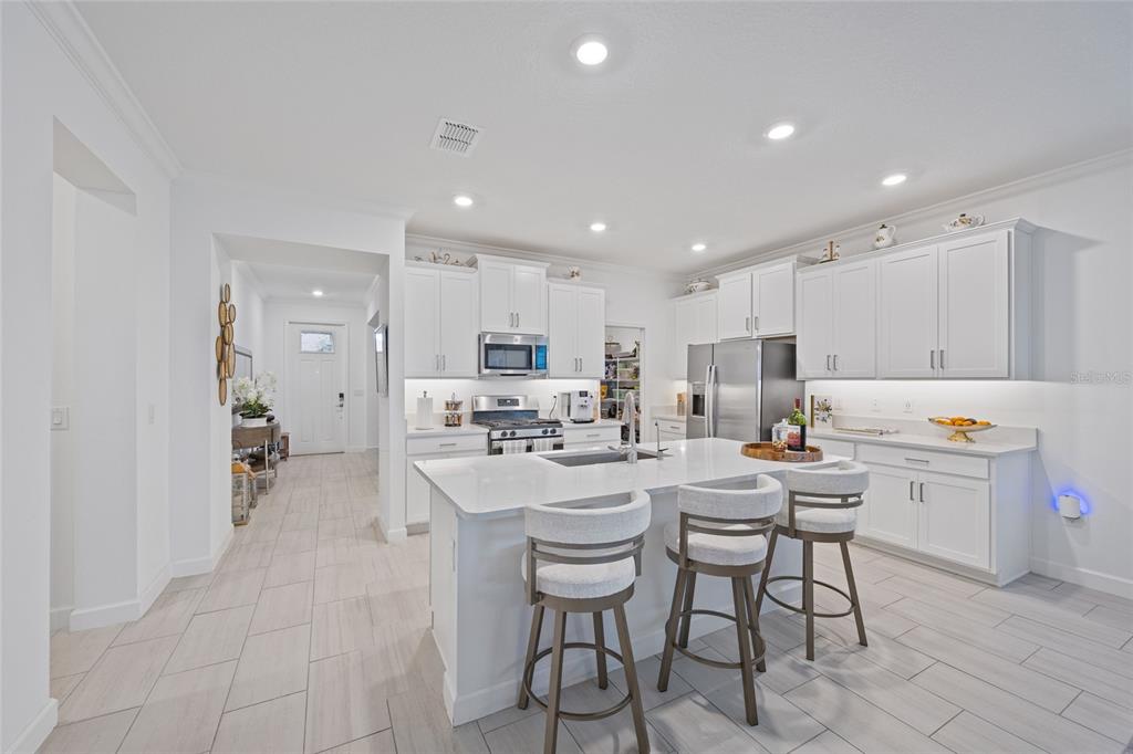 5513 Little Path Drive Wimauma, FL 33598 - Photo 8 of 40 a kitchen with a dining table chairs wooden cabinets and white stainless steel appliances