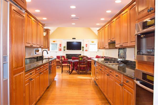 10 Cushing Road Wellesley, MA 02481 - Photo 10 of 20 a large kitchen with stainless steel appliances granite countertop a stove top oven a sink dishwasher a dining table and chairs with wooden floor