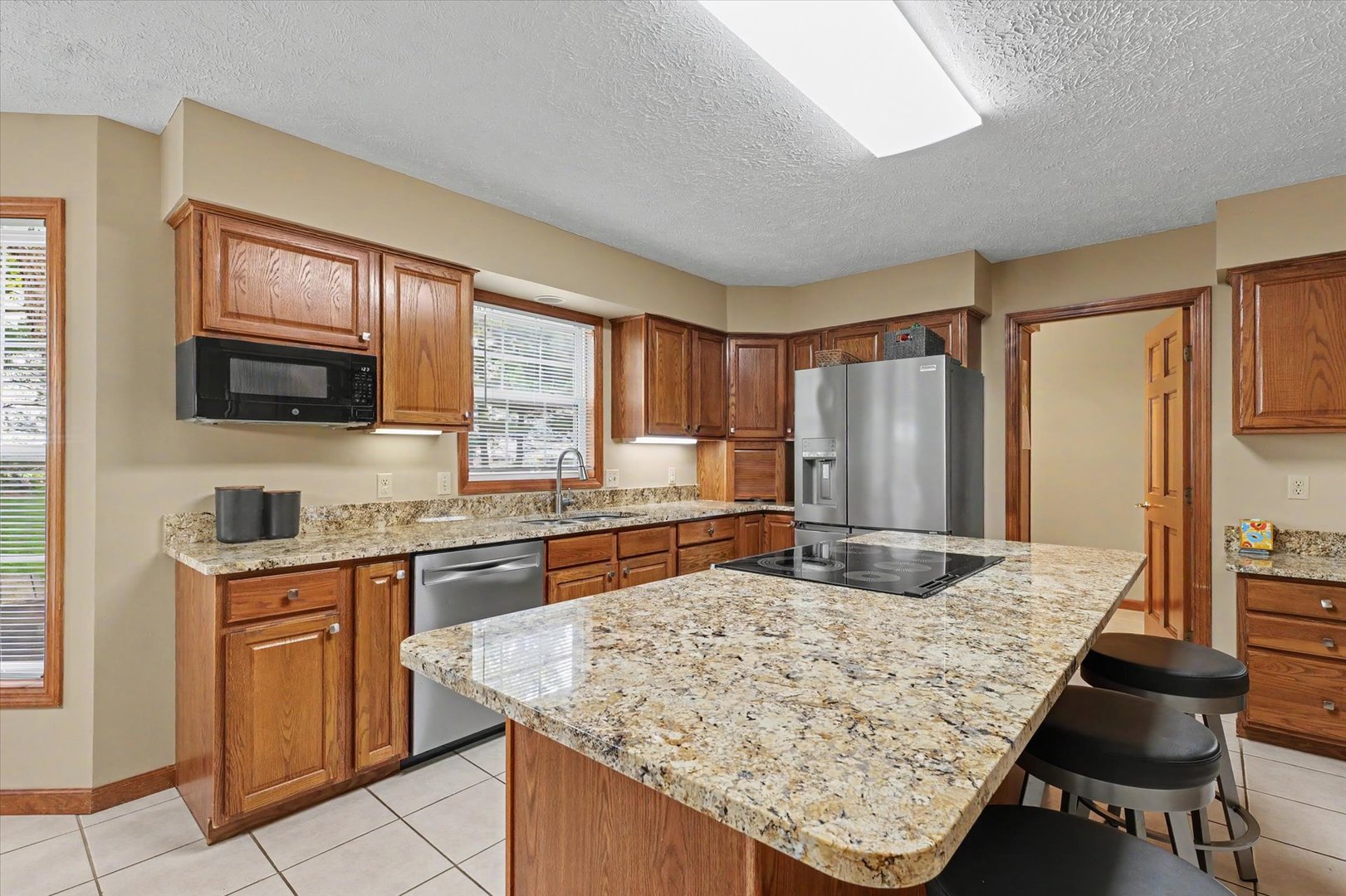 4409 Copper Ridge Road Champaign, IL 61822 - Photo 15 of 40 a kitchen with kitchen island granite countertop wooden cabinets a stove and granite counter tops