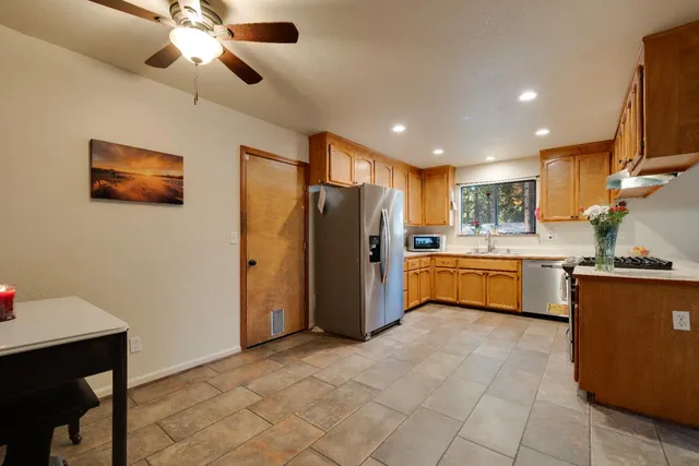 a kitchen with stainless steel appliances kitchen island granite countertop a refrigerator a sink a stove top oven a washer dryer and a dining table