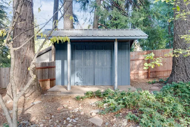 a view of a house with a wooden fence and a tree