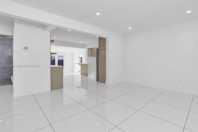 a view of a refrigerator in kitchen and an empty room