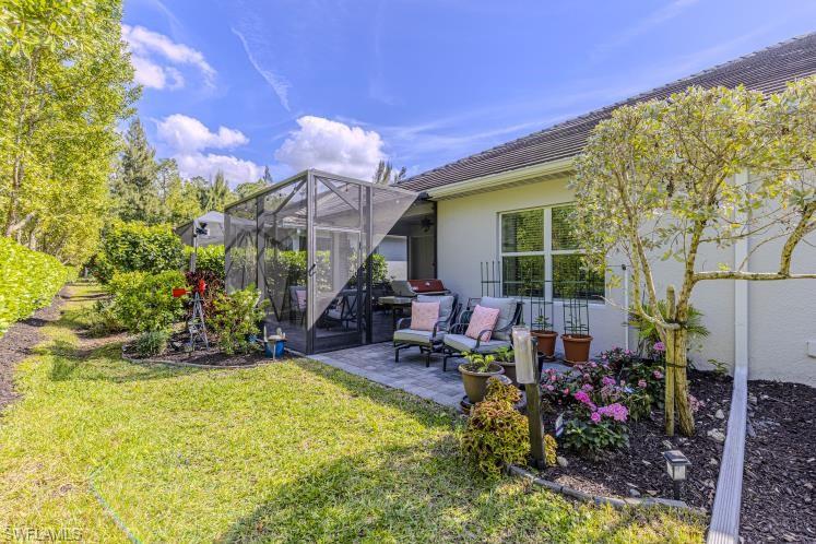 2199 Marquesa Circle Naples, FL 34112 - Photo 16 of 26 View of green lawn with glass enclosure, a sunroom, and a patio area