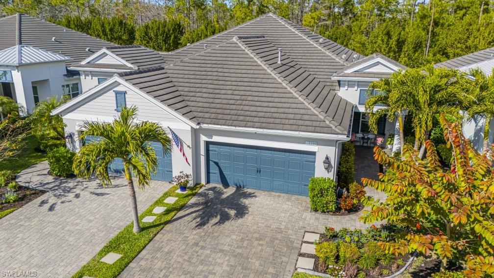 2199 Marquesa Circle Naples, FL 34112 - Photo 18 of 26 View of front of house with a tile roof, driveway, an attached garage, and view of wooded area