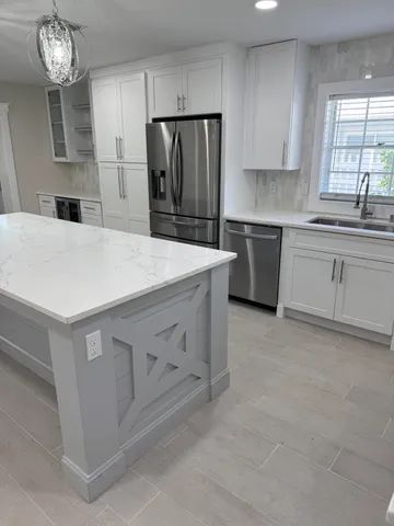 a kitchen with kitchen island white cabinets and refrigerator