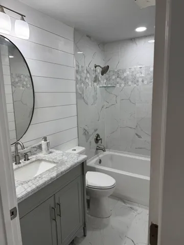 a bathroom with a granite countertop sink a toilet and bathtub