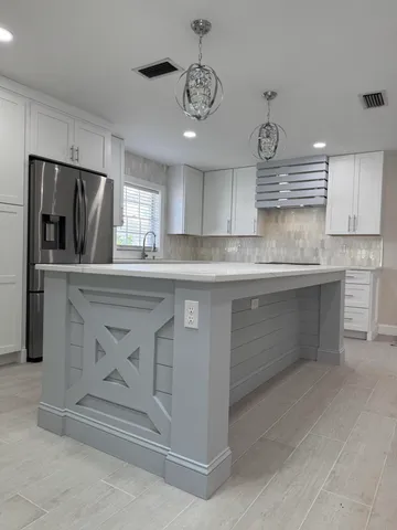 a kitchen with stainless steel appliances granite countertop a sink a stove a refrigerator cabinets and a window