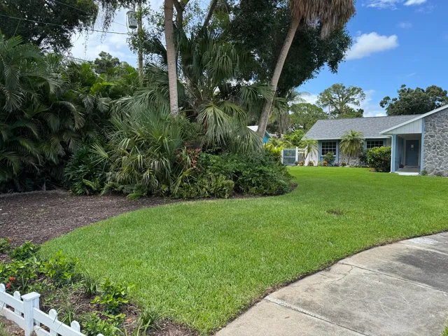 a view of a house with a big yard and potted plants