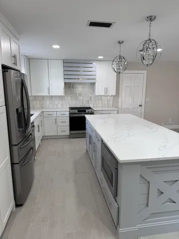 a kitchen with stainless steel appliances a refrigerator a sink a stove and cabinets