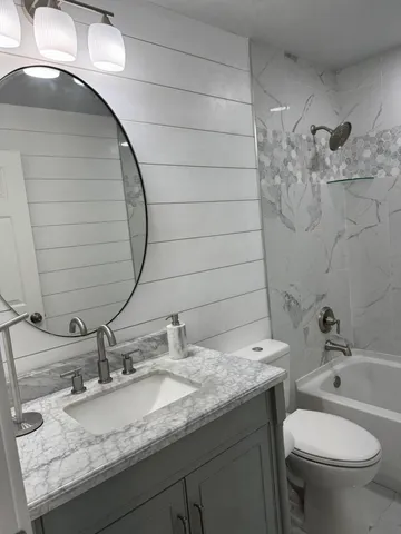 a bathroom with a granite countertop sink a toilet and mirror