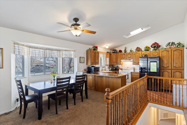 5321 South 3100th Street West Roy, UT 84067 - Photo 32 of 64 Carpeted dining area featuring a bay window, ceiling fan with light fixture, and wood railing