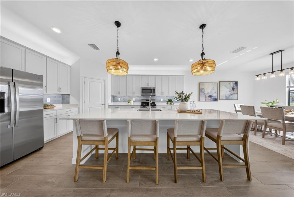21082 Verawood Loop Estero, FL 33928 - Photo 9 of 50 a kitchen with stainless steel appliances granite countertop a sink a stove and chairs