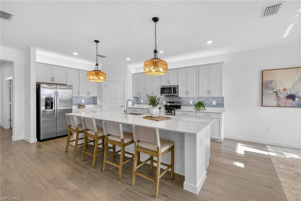 21082 Verawood Loop Estero, FL 33928 - Photo 10 of 50 a kitchen with stainless steel appliances kitchen island granite countertop a refrigerator a stove a dining table and chairs with wooden floor
