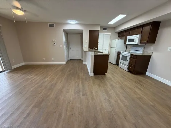 a view of kitchen with microwave a refrigerator and cabinets