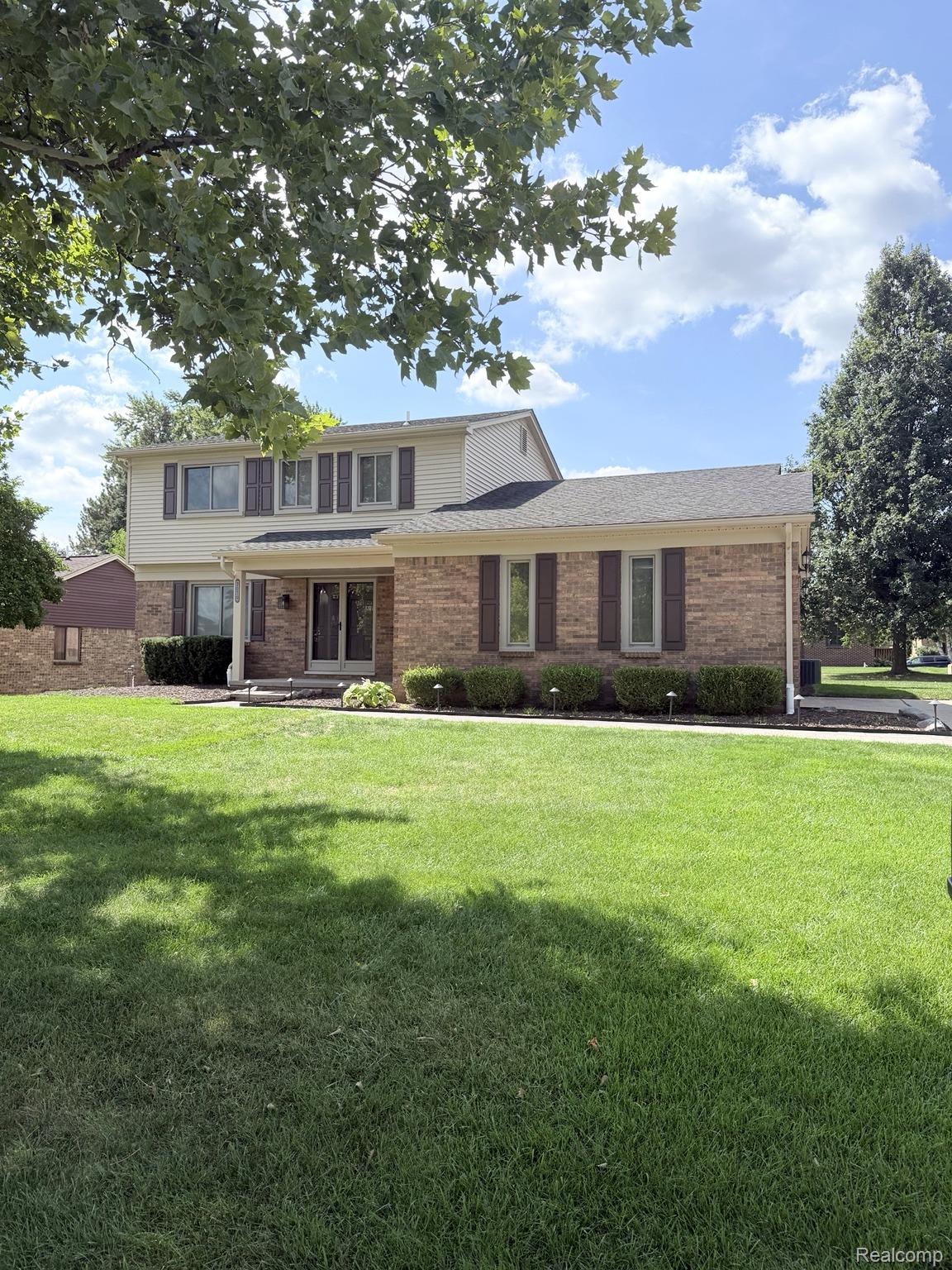 2070 Winchester Road Rochester, MI 48307 - Photo 1 of 34 Brick exterior with light-colored siding, a dark roof, and a well-maintained lawn