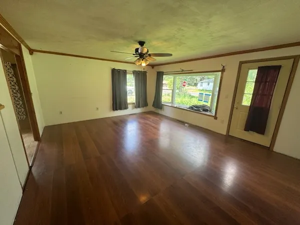 an empty room with wooden floor and windows