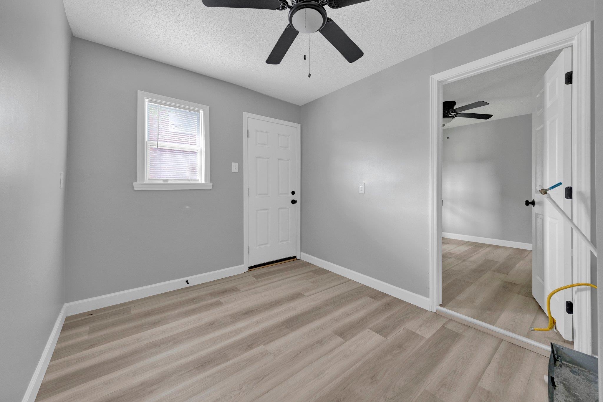 Unfurnished bedroom featuring a textured ceiling, light wood-style floors, and ceiling fan