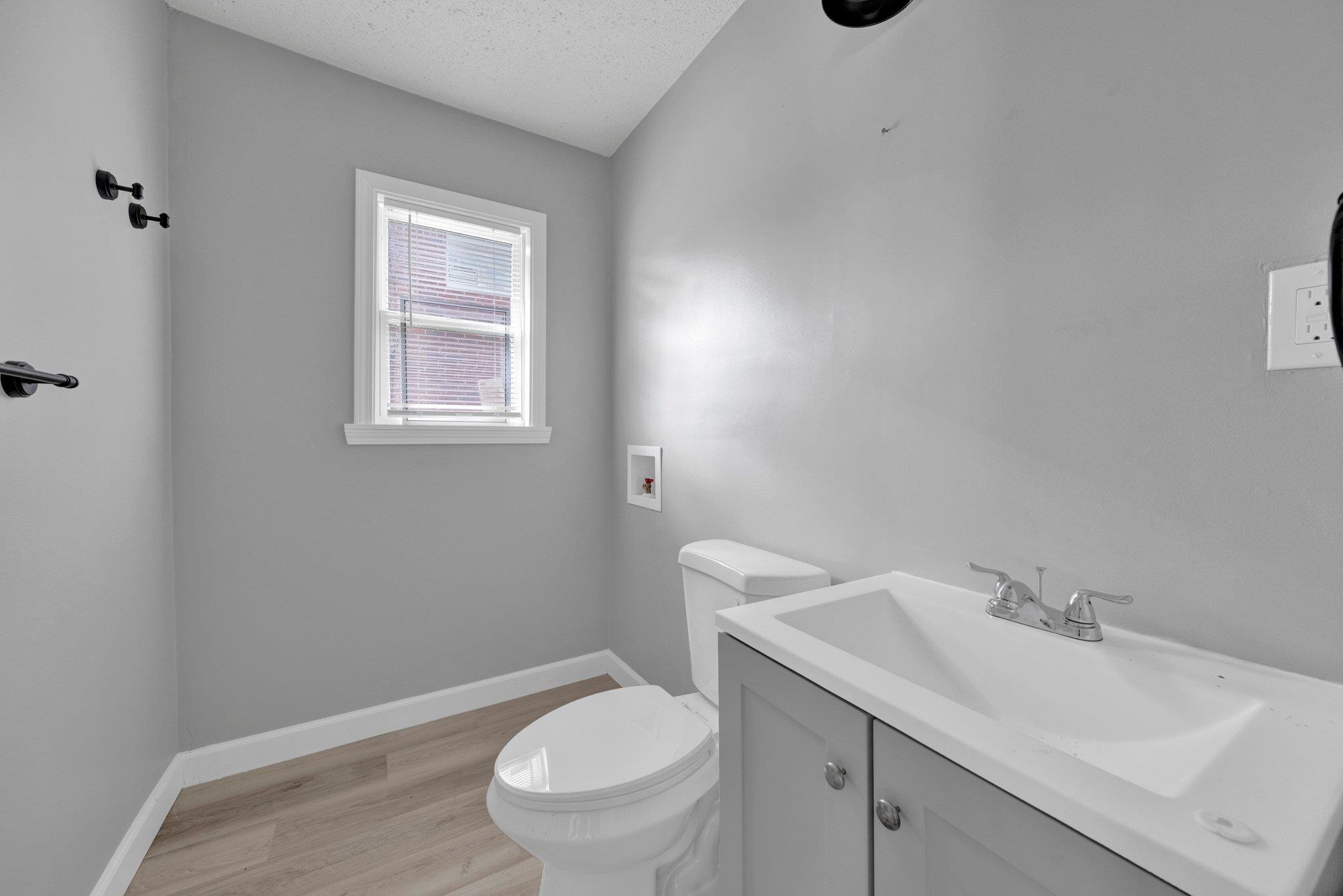 160 Silverage Avenue Memphis, TN 38109 - Photo 11 of 11 Half bath with vanity, a textured ceiling, and light wood-style flooring