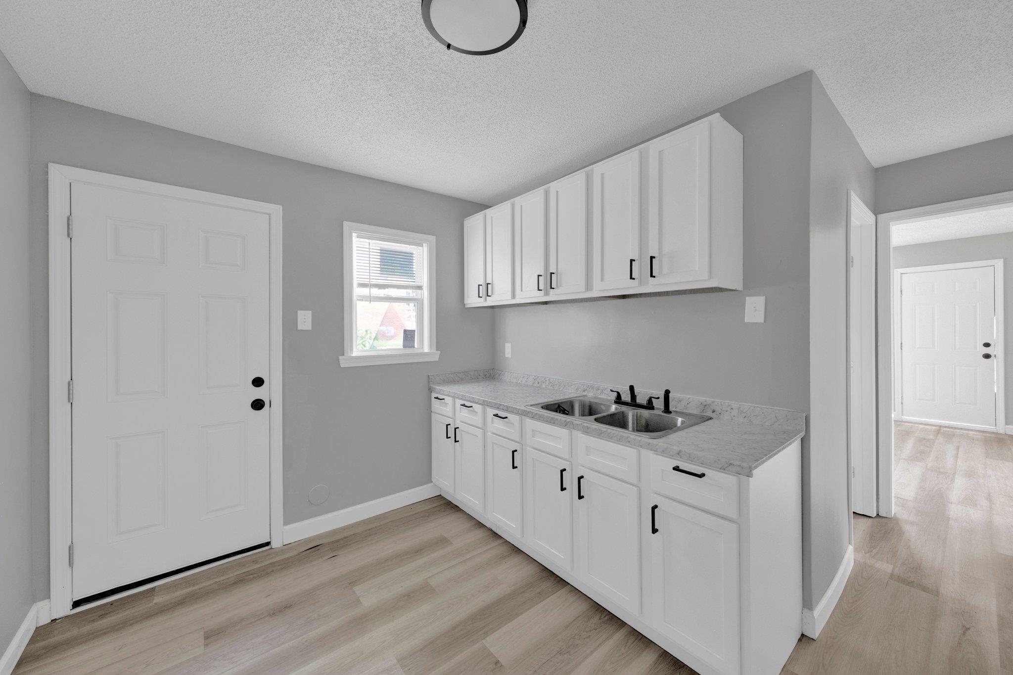 160 Silverage Avenue Memphis, TN 38109 - Photo 3 of 11 Kitchen with a textured ceiling, white cabinets, light wood-type flooring, and light stone countertops