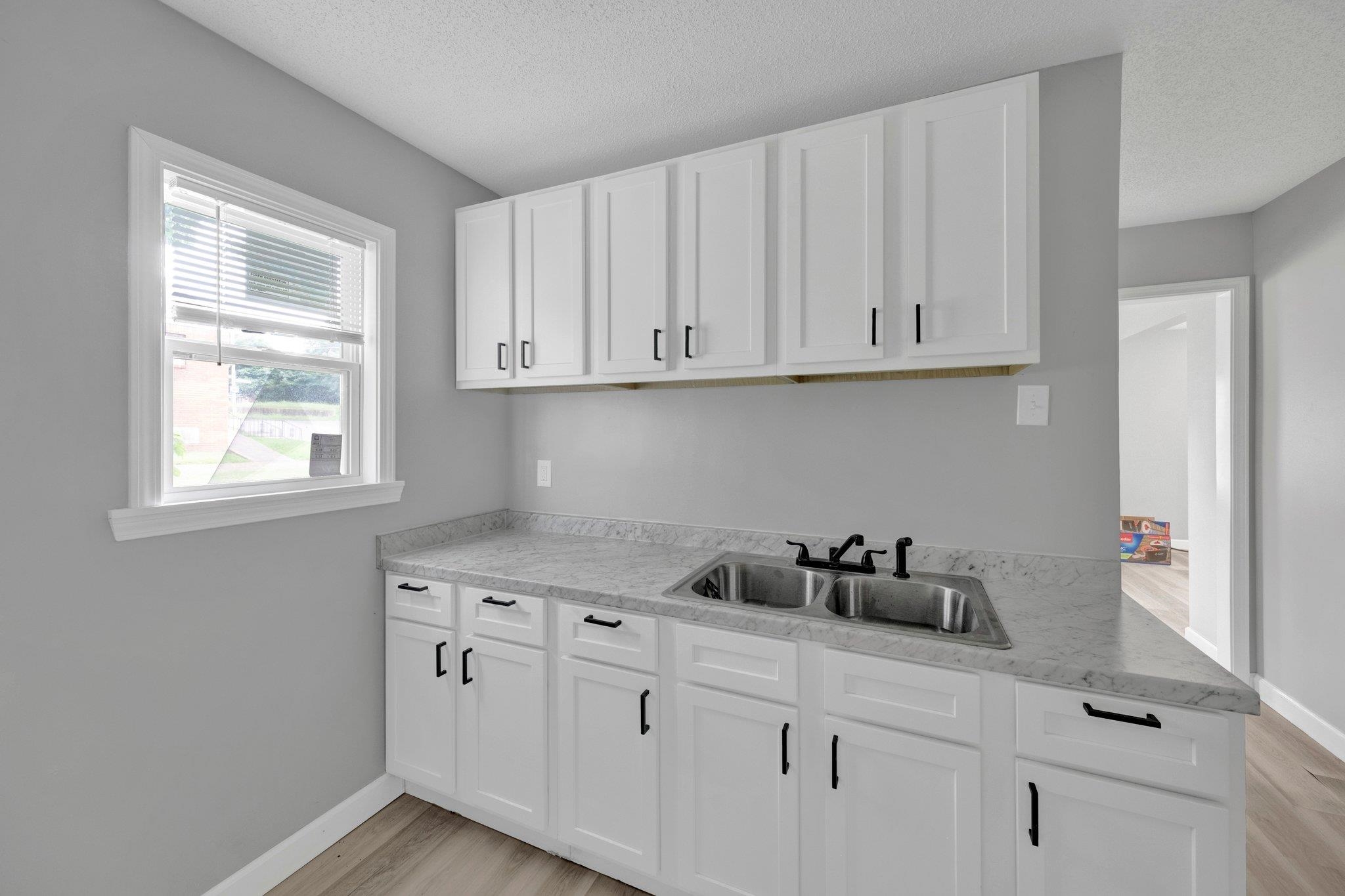160 Silverage Avenue Memphis, TN 38109 - Photo 4 of 11 Kitchen with light countertops, white cabinetry, a textured ceiling, and light wood-style floors