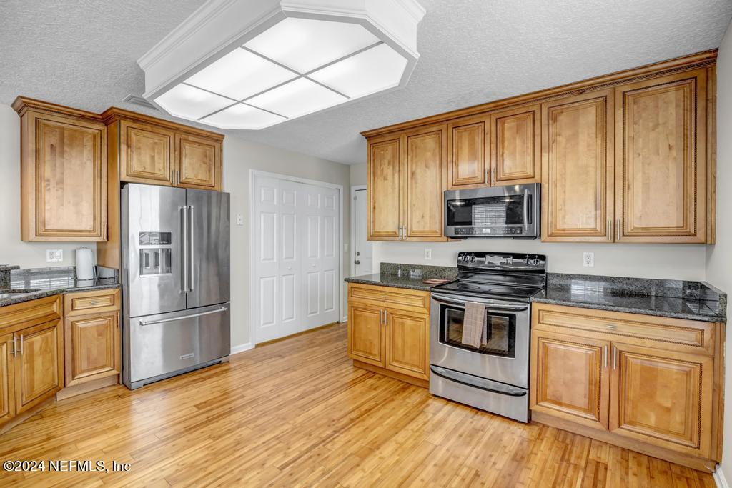 3308 Thunder Road Middleburg, FL 32068 - Photo 11 of 39 a kitchen with stainless steel appliances granite countertop a stove a sink dishwasher a refrigerator and a microwave oven with wooden floor