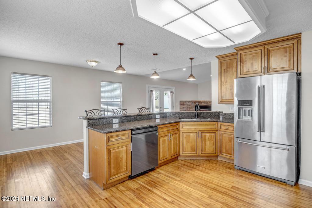 3308 Thunder Road Middleburg, FL 32068 - Photo 12 of 39 a kitchen with stainless steel appliances granite countertop a refrigerator a sink dishwasher a stove and white countertops with wooden floor
