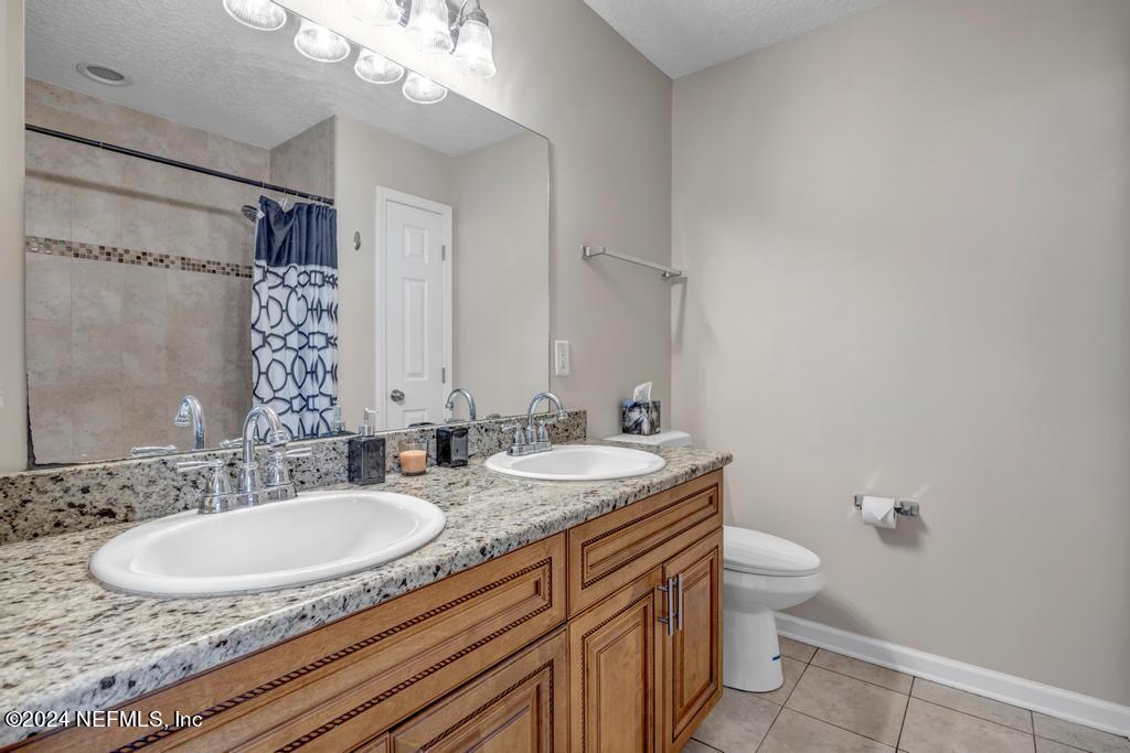 3308 Thunder Road Middleburg, FL 32068 - Photo 18 of 39 a bathroom with a granite countertop sink a mirror and a toilet