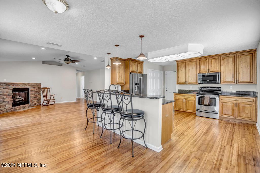 3308 Thunder Road Middleburg, FL 32068 - Photo 10 of 39 a kitchen with stainless steel appliances kitchen island granite countertop a stove top oven a sink a dining table and chairs with wooden floor