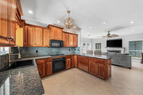 a large kitchen with stainless steel appliances granite countertop a stove top oven a sink dishwasher a dining table and chairs with wooden floor
