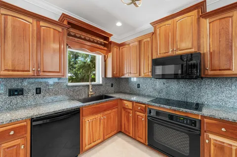 a large kitchen with stainless steel appliances granite countertop a stove top oven a sink dishwasher a dining table and chairs with wooden floor
