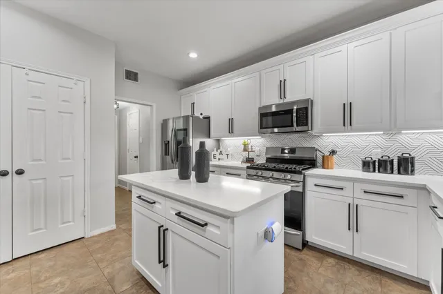 a kitchen with white cabinets and stainless steel appliances