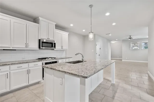 a kitchen with kitchen island granite countertop white cabinets and stainless steel appliances
