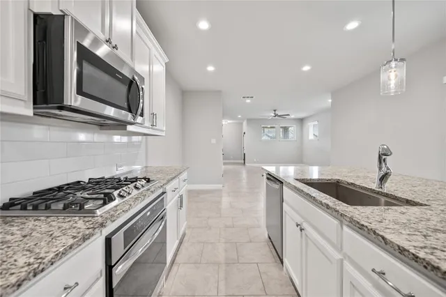 a kitchen with stainless steel appliances granite countertop a sink stove and microwave