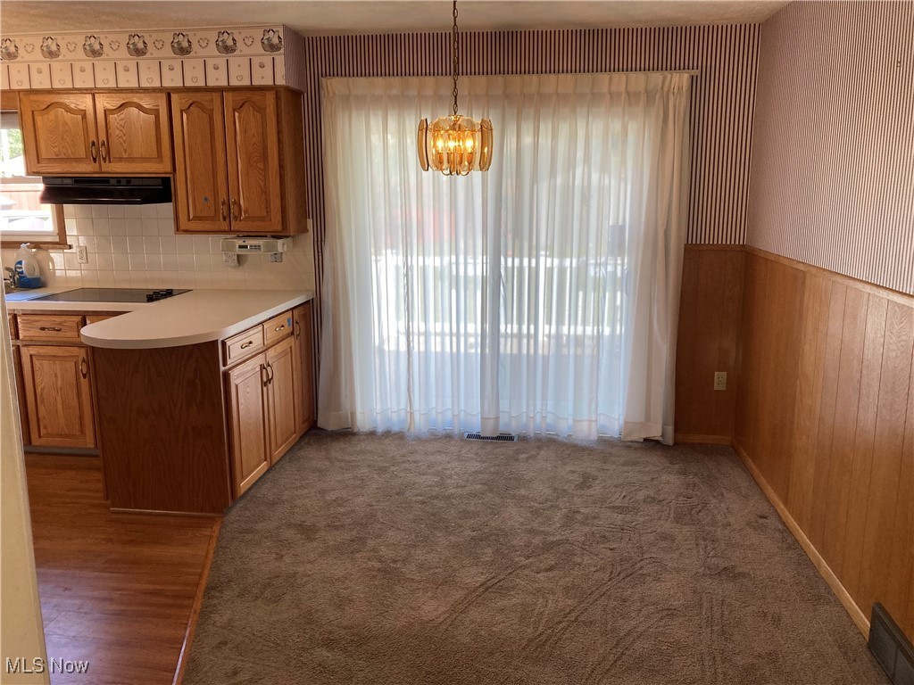 2547 Mayfair Road Akron, OH 44312 - Photo 9 of 50 Kitchen with pendant lighting, tasteful backsplash, wooden walls, a chandelier, and hardwood / wood-style floors
