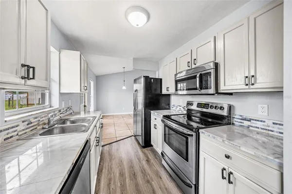 a kitchen with stainless steel appliances granite countertop a stove top oven a sink dishwasher a refrigerator and cabinets with wooden floor