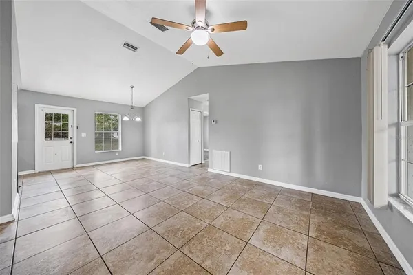 a view of an empty room with window and chandelier fan