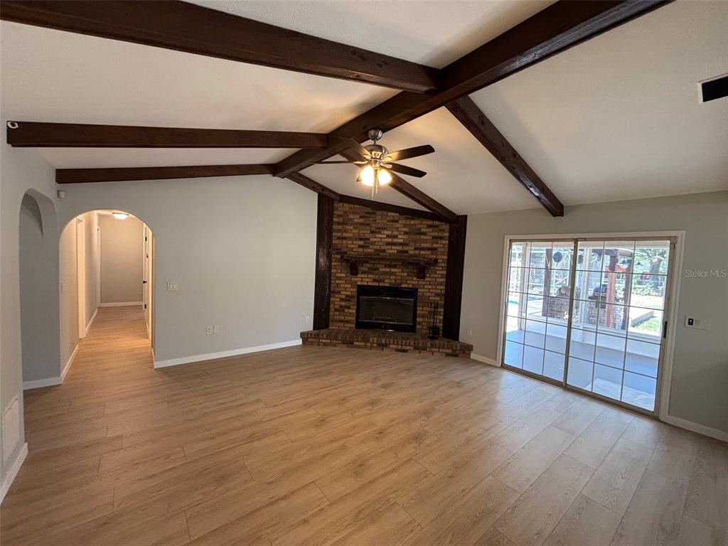 9801 Southeast Sunset Harbor Road Summerfield, FL 34491 - Photo 7 of 37 an empty room with wooden floor fireplace and windows