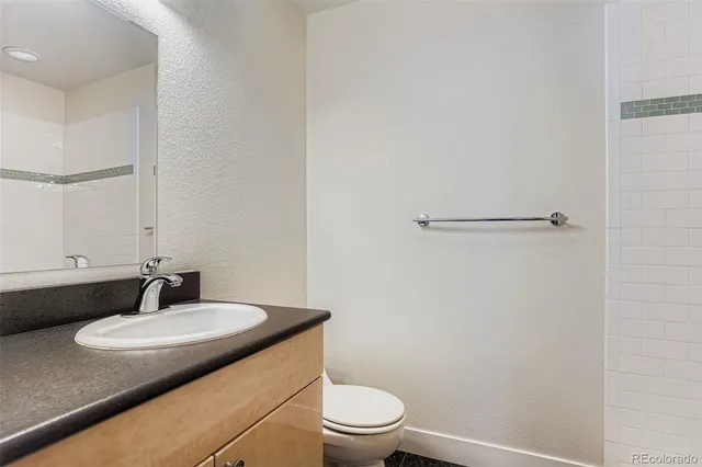 a bathroom with a granite countertop sink toilet and a mirror