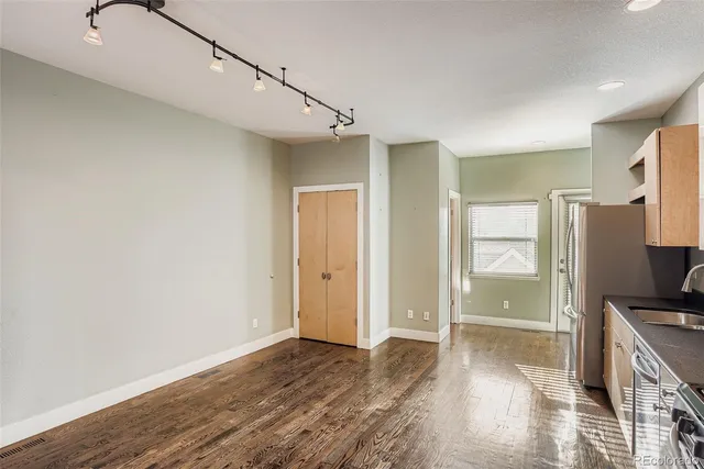 a view of a hallway with wooden floor and a bathroom