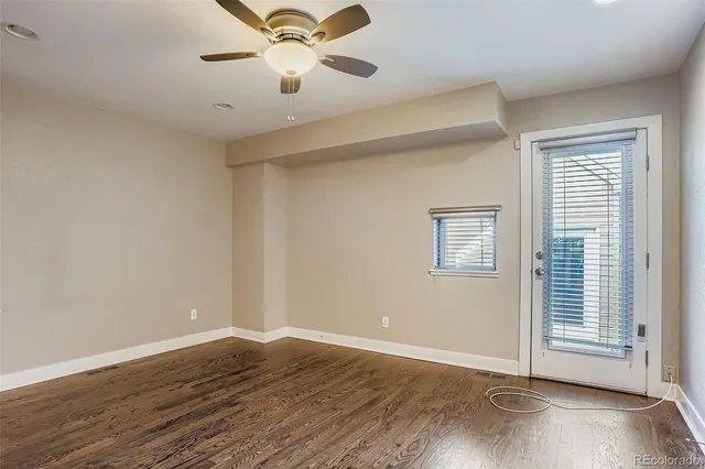 an empty room with wooden floor fan and windows