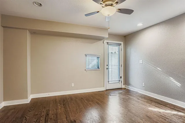 an empty room with wooden floor and fan