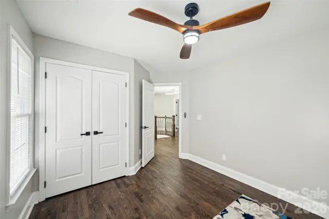 an empty room with wooden floor closet and windows
