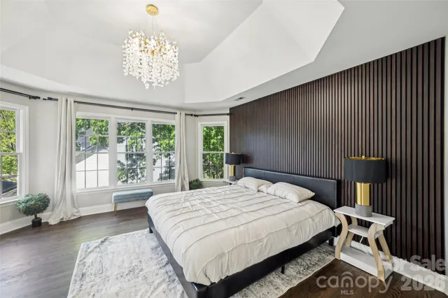 a bedroom with a large bed and a chandelier next to a window