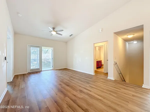 a view of an empty room with window and wooden floor